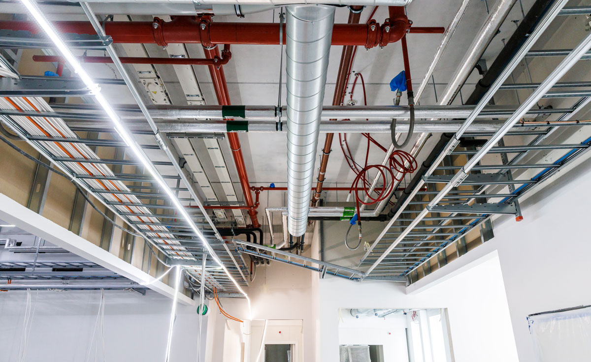 Cable ladders carrying cables along the ceiling of a commercial building under construction